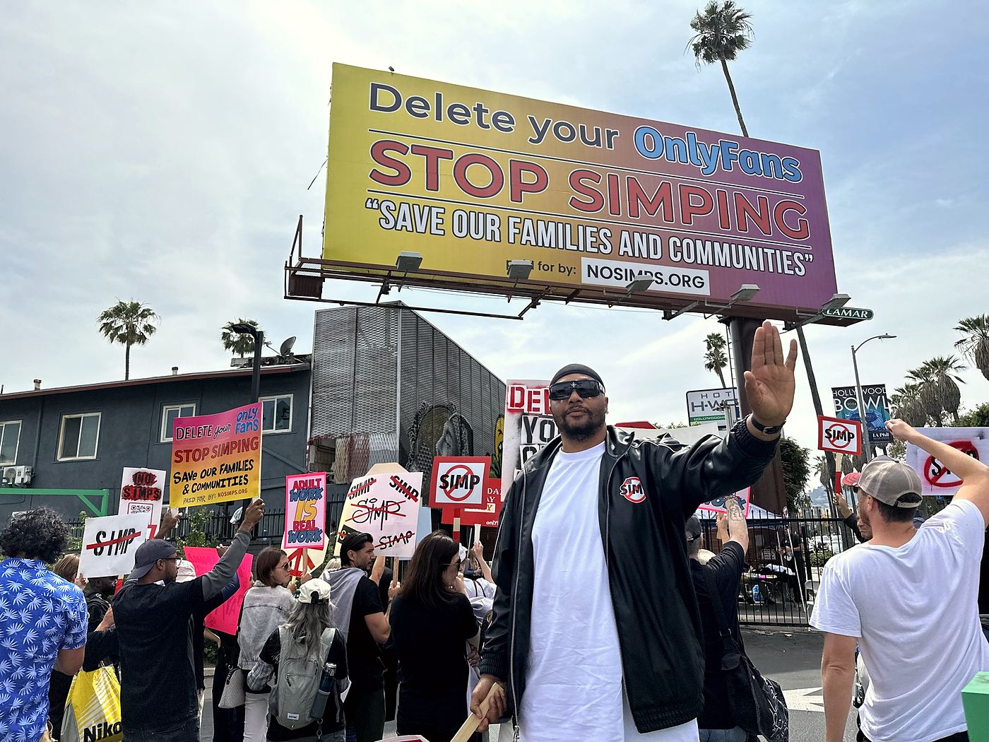 Crowd with signs beneath the Delete Your OnlyFans billboard on Sunset Boulevard