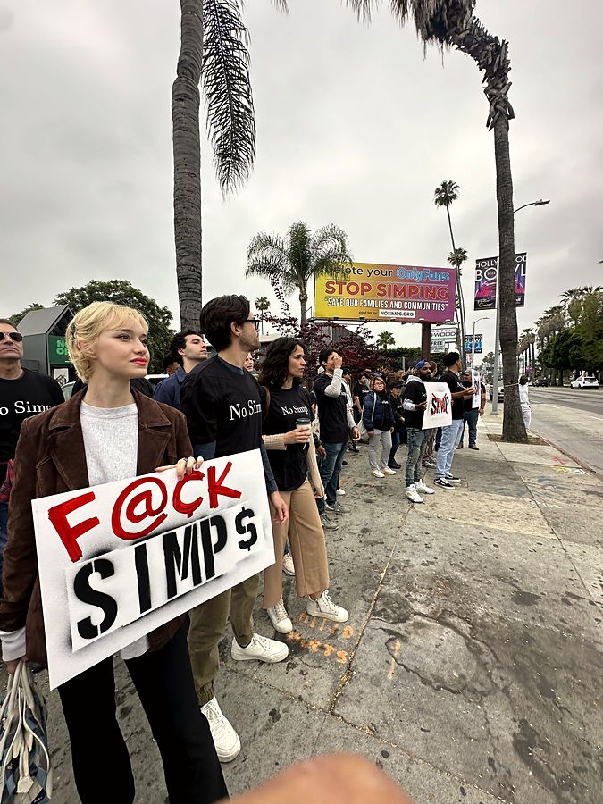 Marcher holding a spray-stencilled sign under the Hollywood billboard