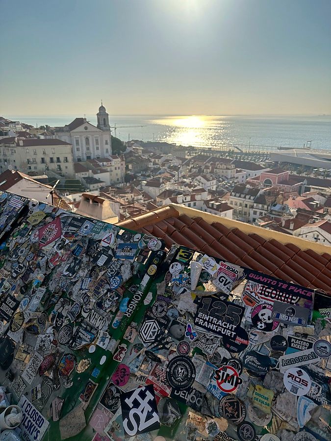 A NO SIMP sticker on a crowded sticker wall at a Lisbon viewpoint